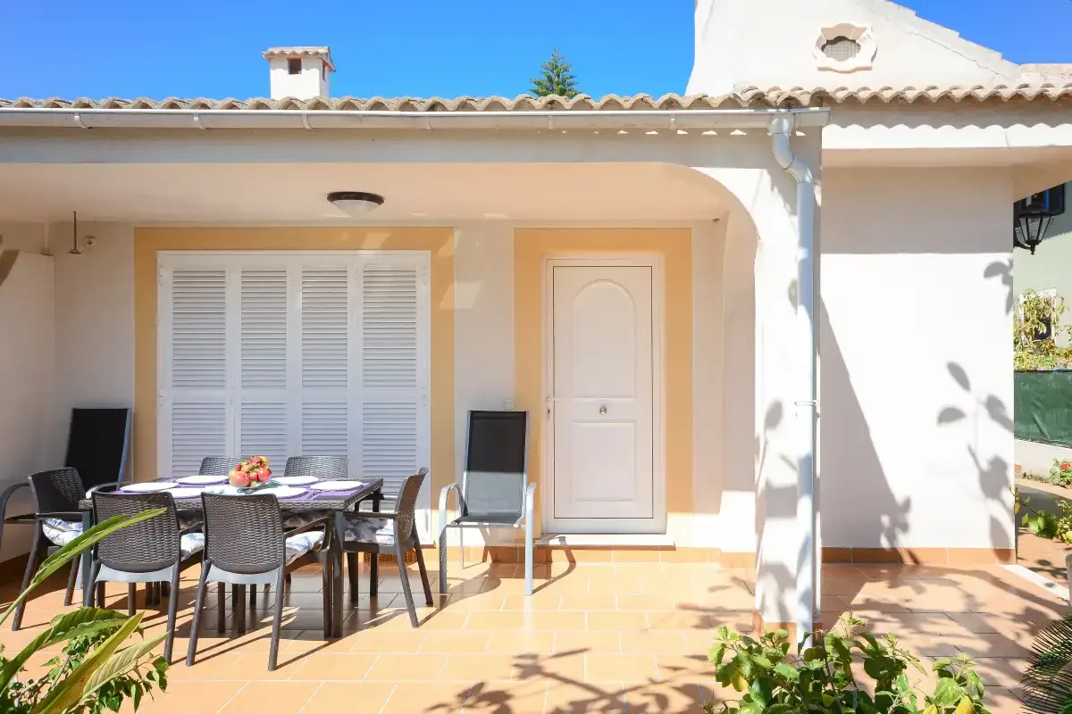 Un patio cubierto con asientos y una mesa junto a la casa.