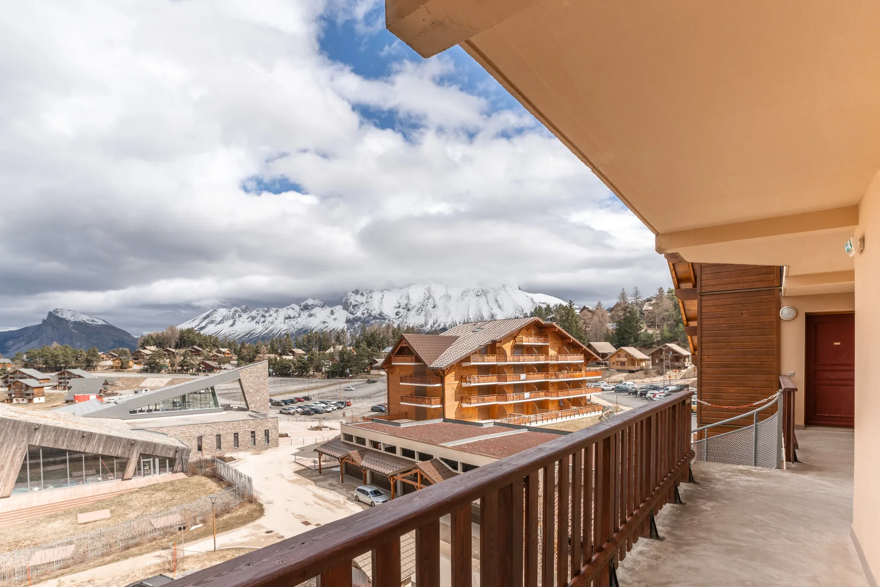 Balcony overlooking wooden buildings and snow-covered mountains.