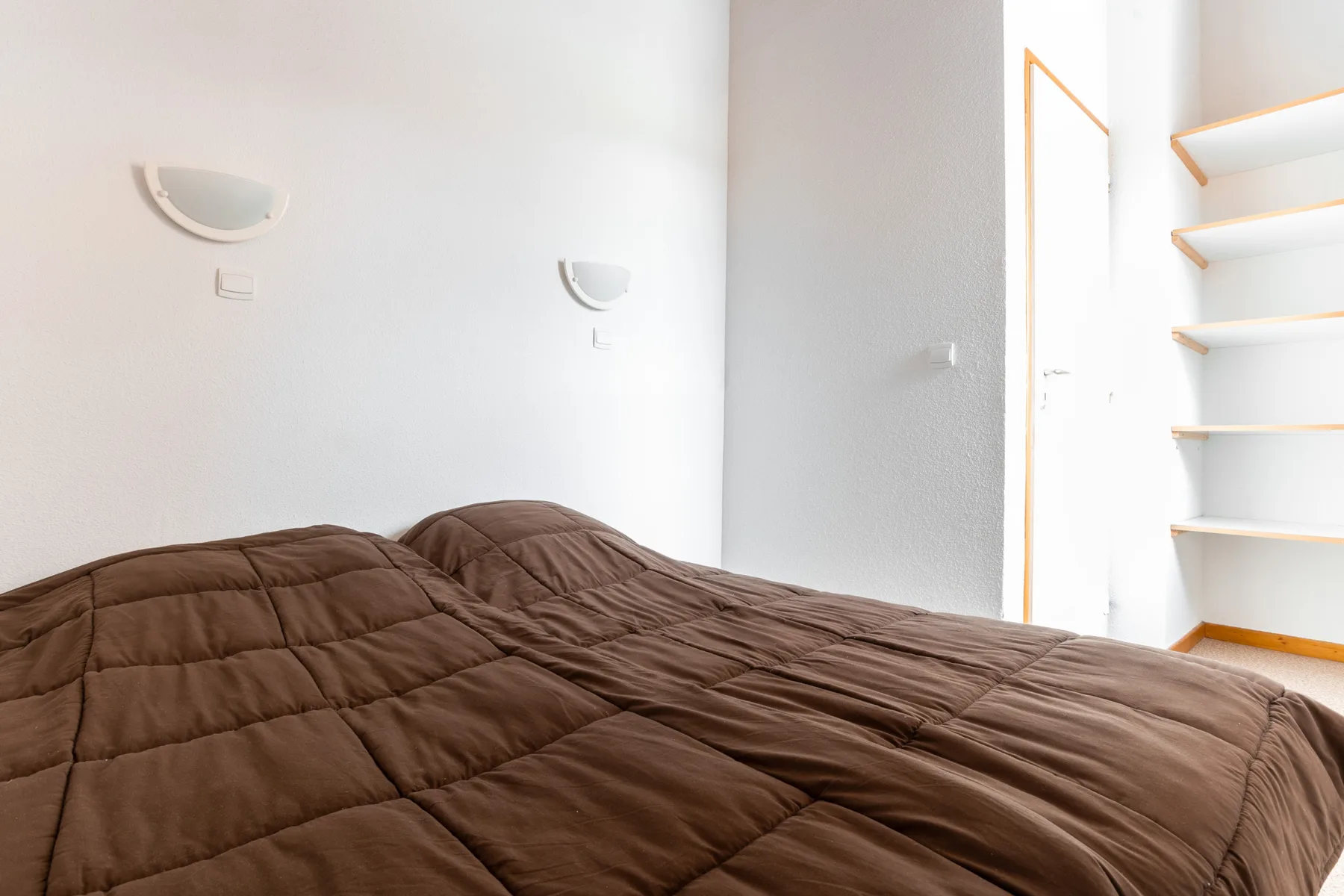 Bedroom with brown bedding and built-in shelves.