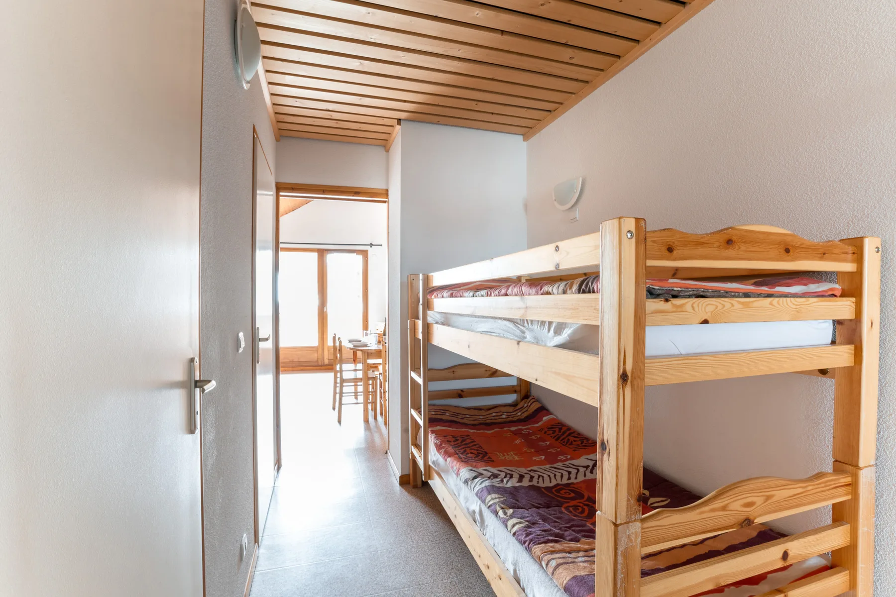 A bedroom with wooden bunk beds and a slatted ceiling.
