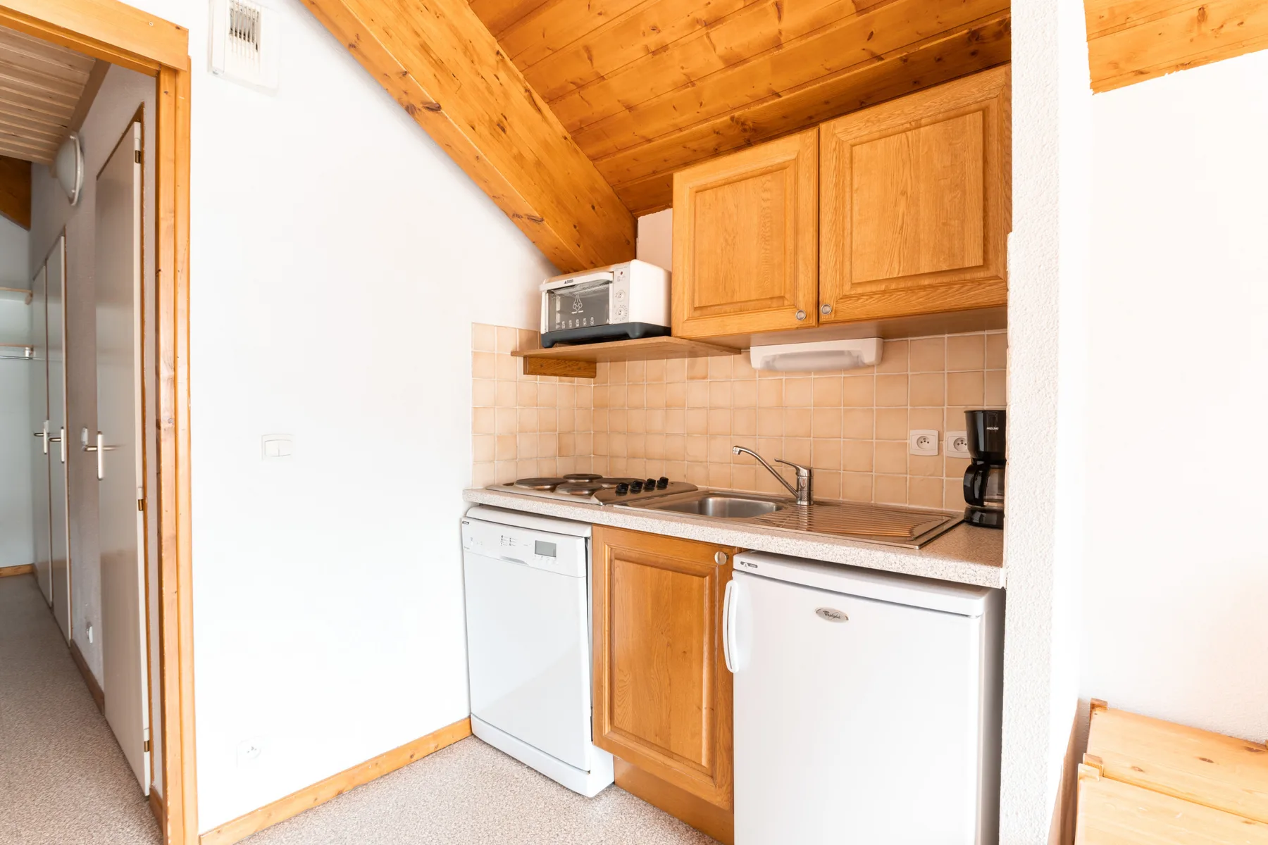 A compact kitchen with wooden cabinets and countertop appliances.