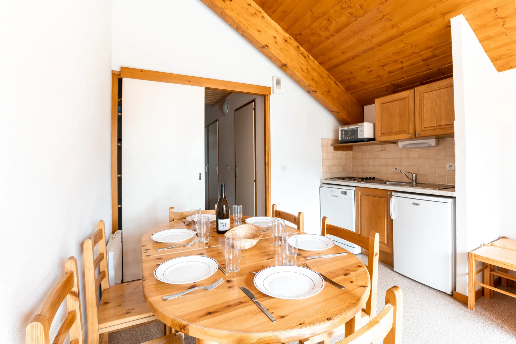 A dining area with a wooden table set beside a compact kitchen.