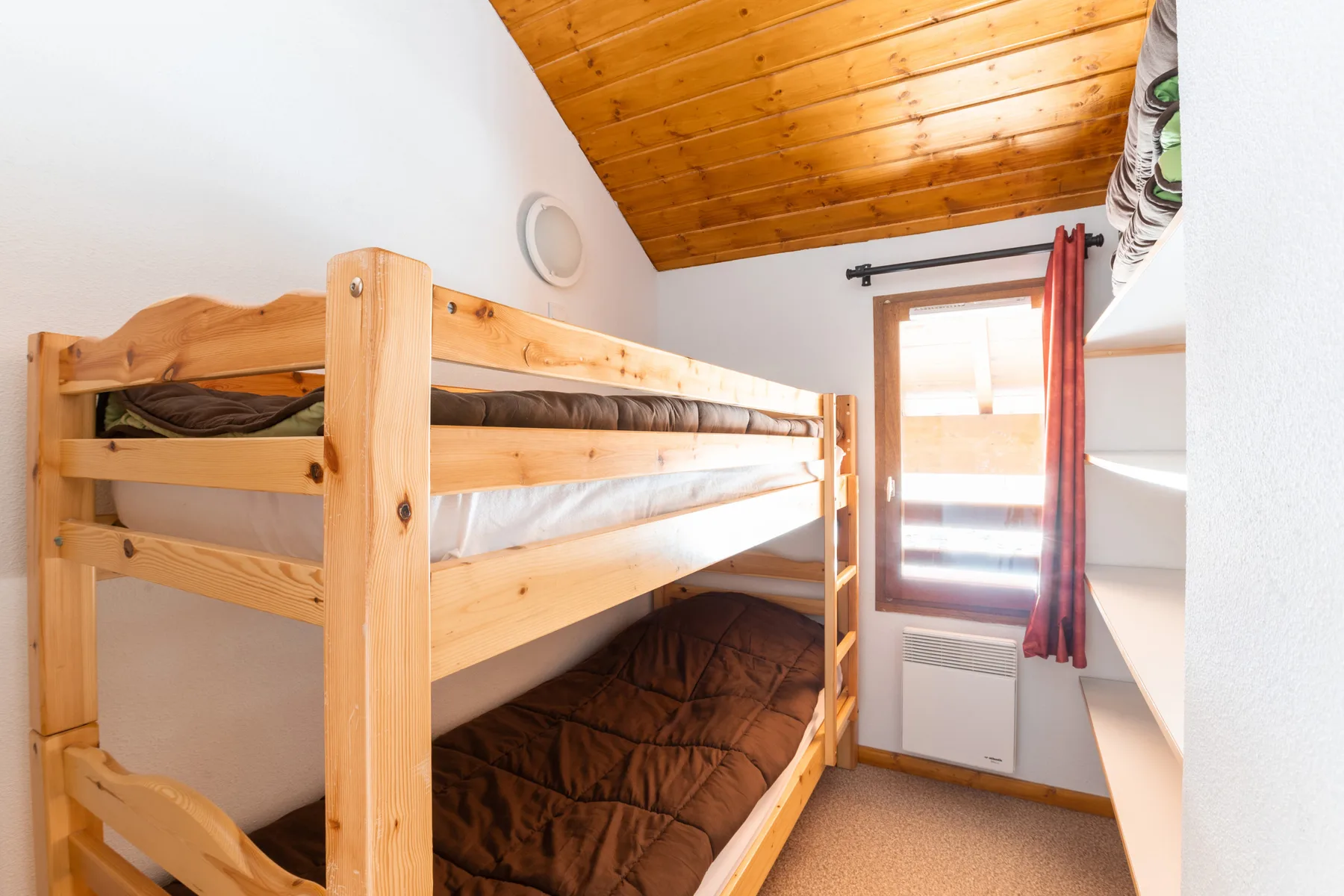 A bunk bedroom with wooden beds and a window.
