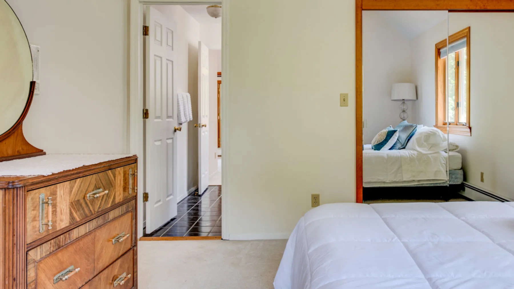 Un dormitorio con una cama en primer plano y una cómoda junto a la puerta.