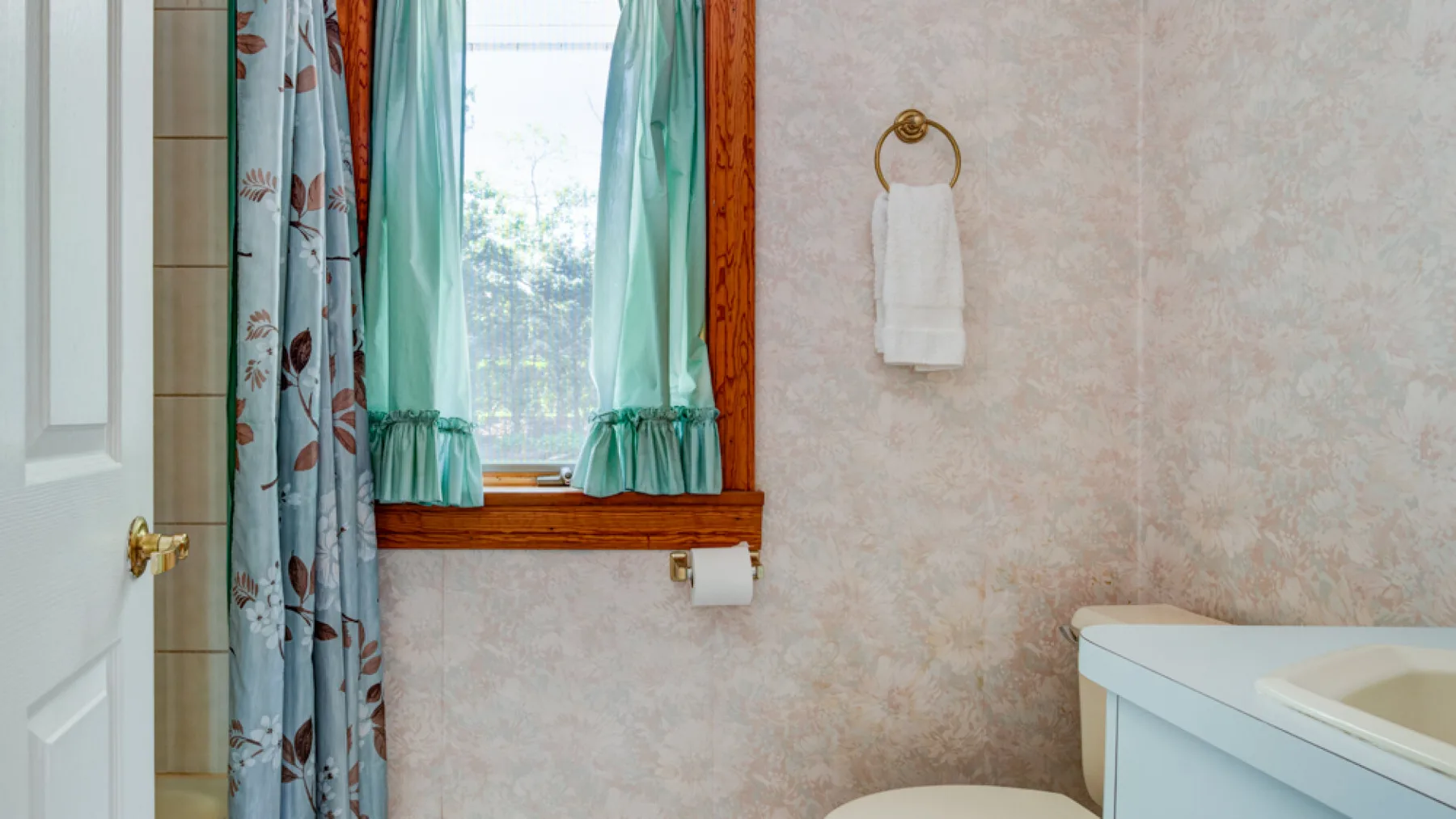 Un baño con bañera, ventana y cortinas estampadas.