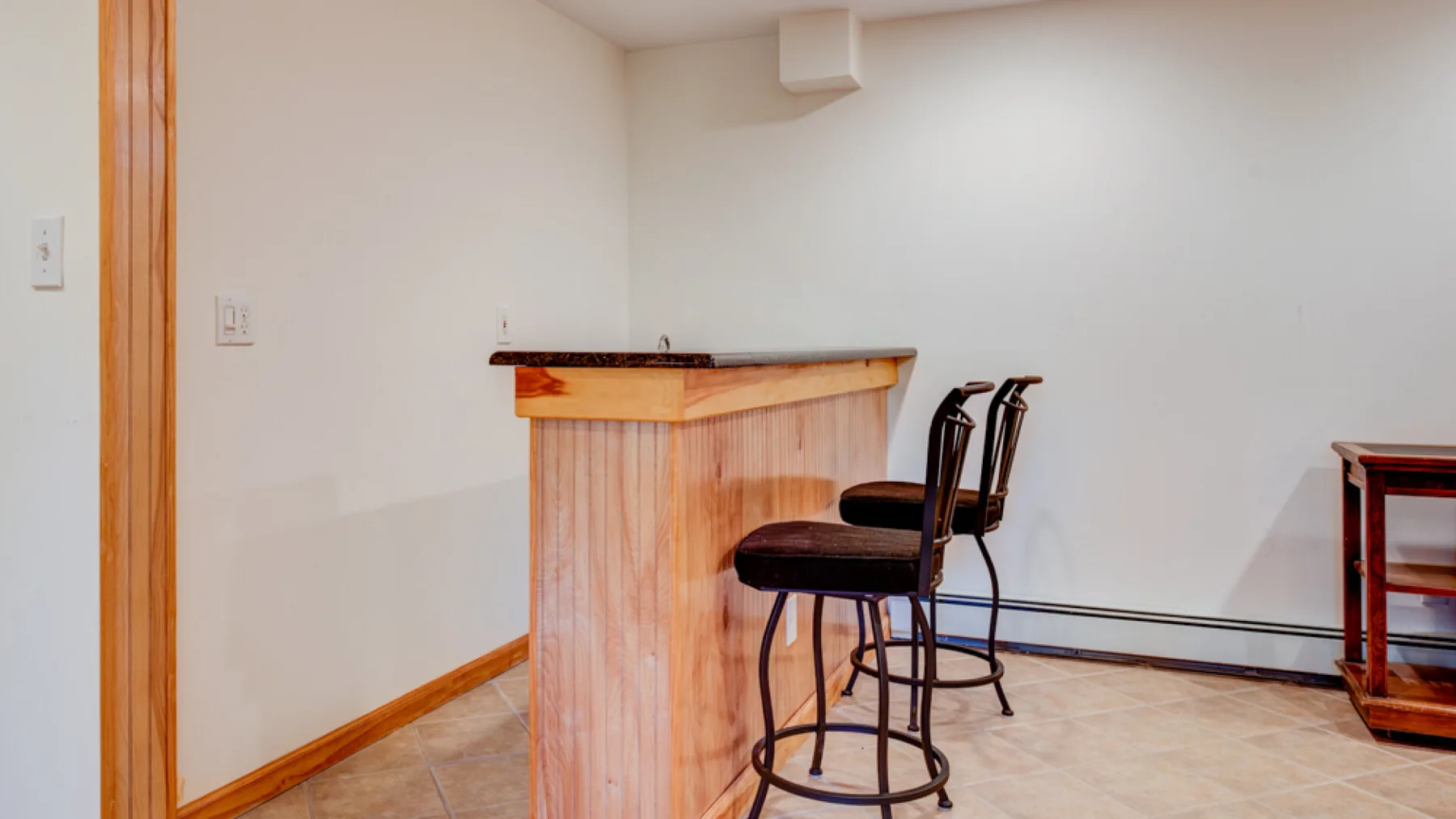 Una habitación pequeña con una barra de madera y dos asientos altos.