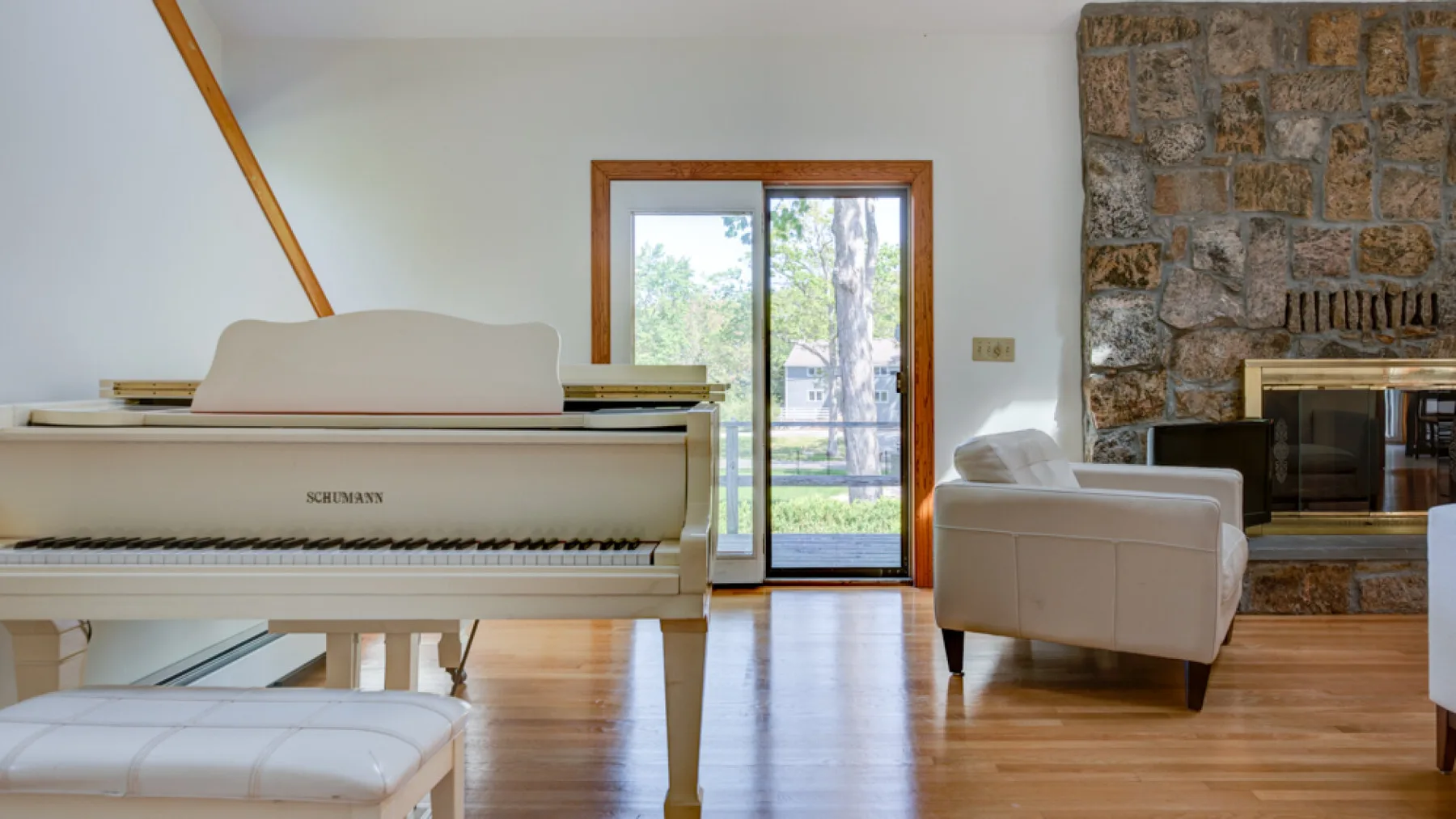 Una sala de estar con un piano, asientos y una chimenea de piedra.