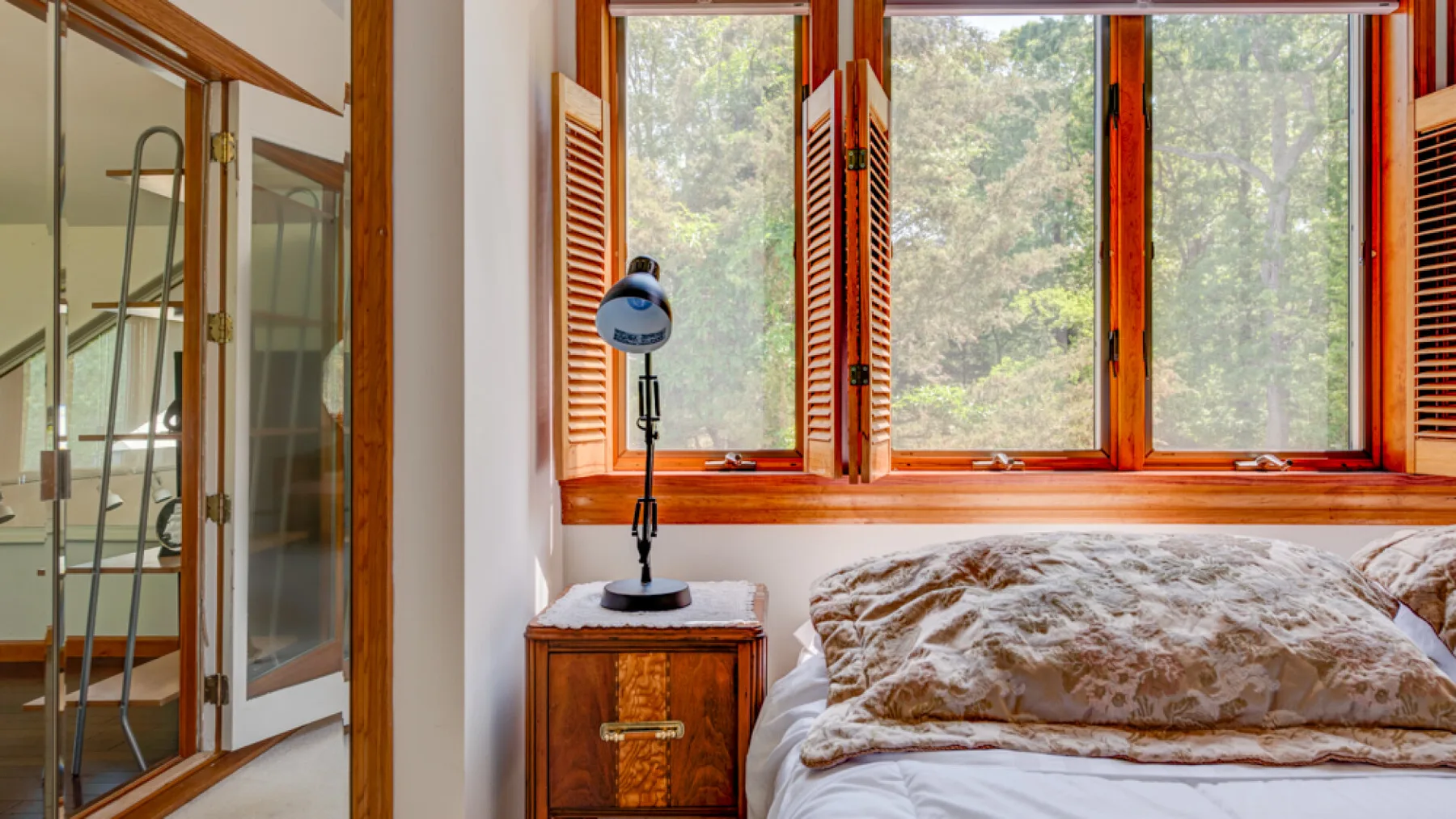 Un dormitorio con una cama junto a grandes ventanas y una ducha acristalada.