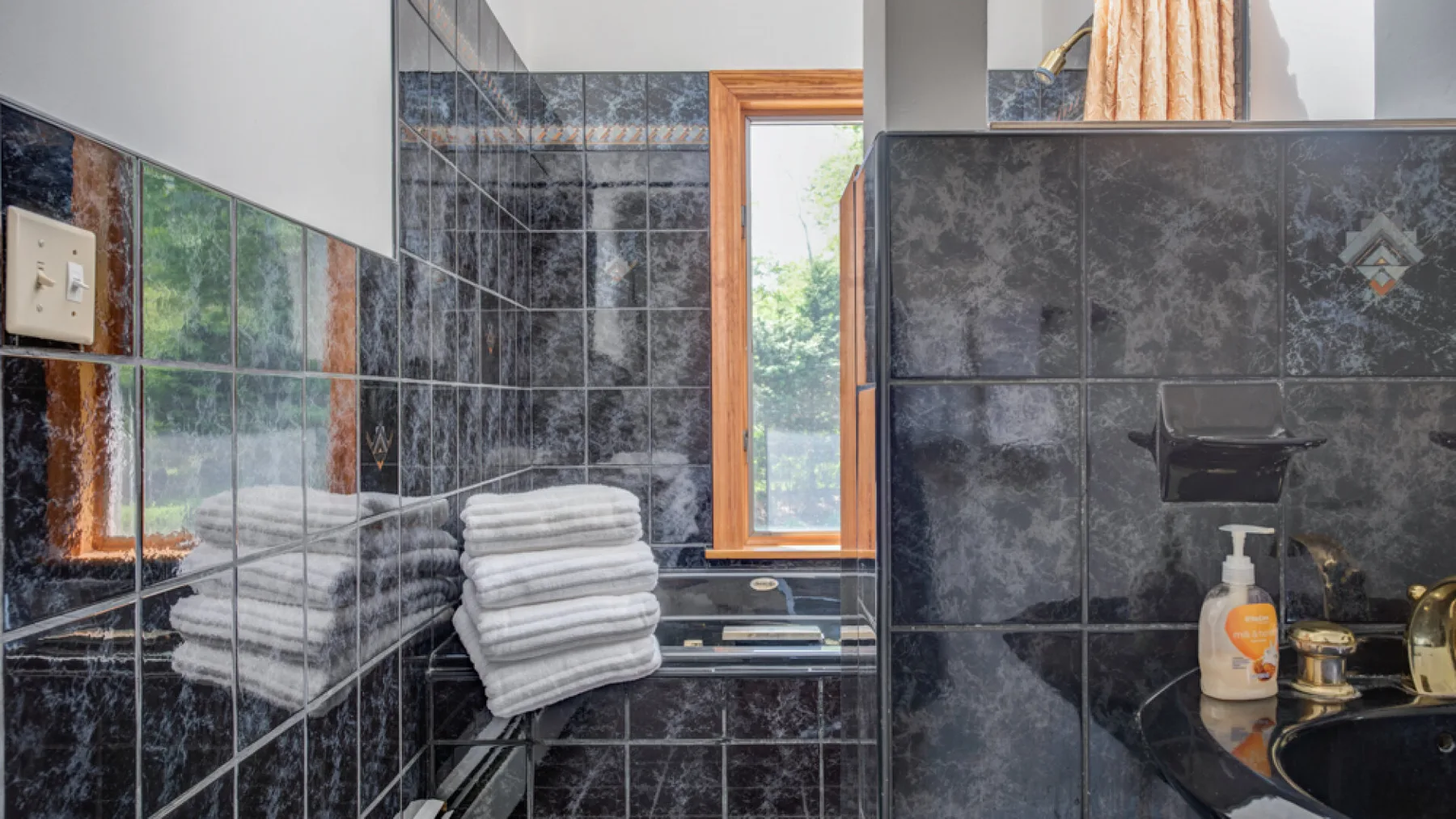 Un baño alicatado con lavabo y toallas blancas dobladas junto a una ventana.