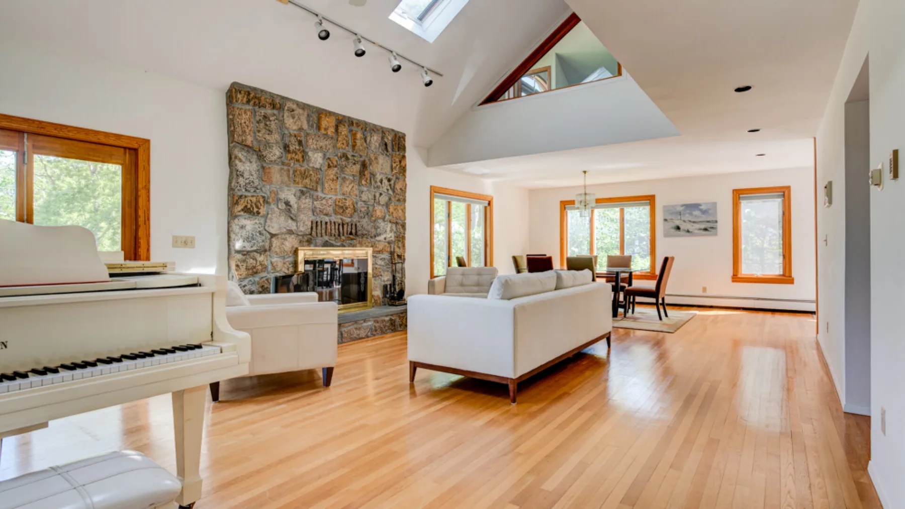 Una sala luminosa con chimenea de piedra, asientos y ventanas grandes.