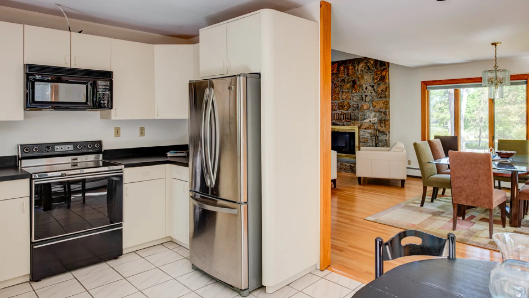 Una cocina se abre a un comedor con grandes ventanas y suelo de madera.