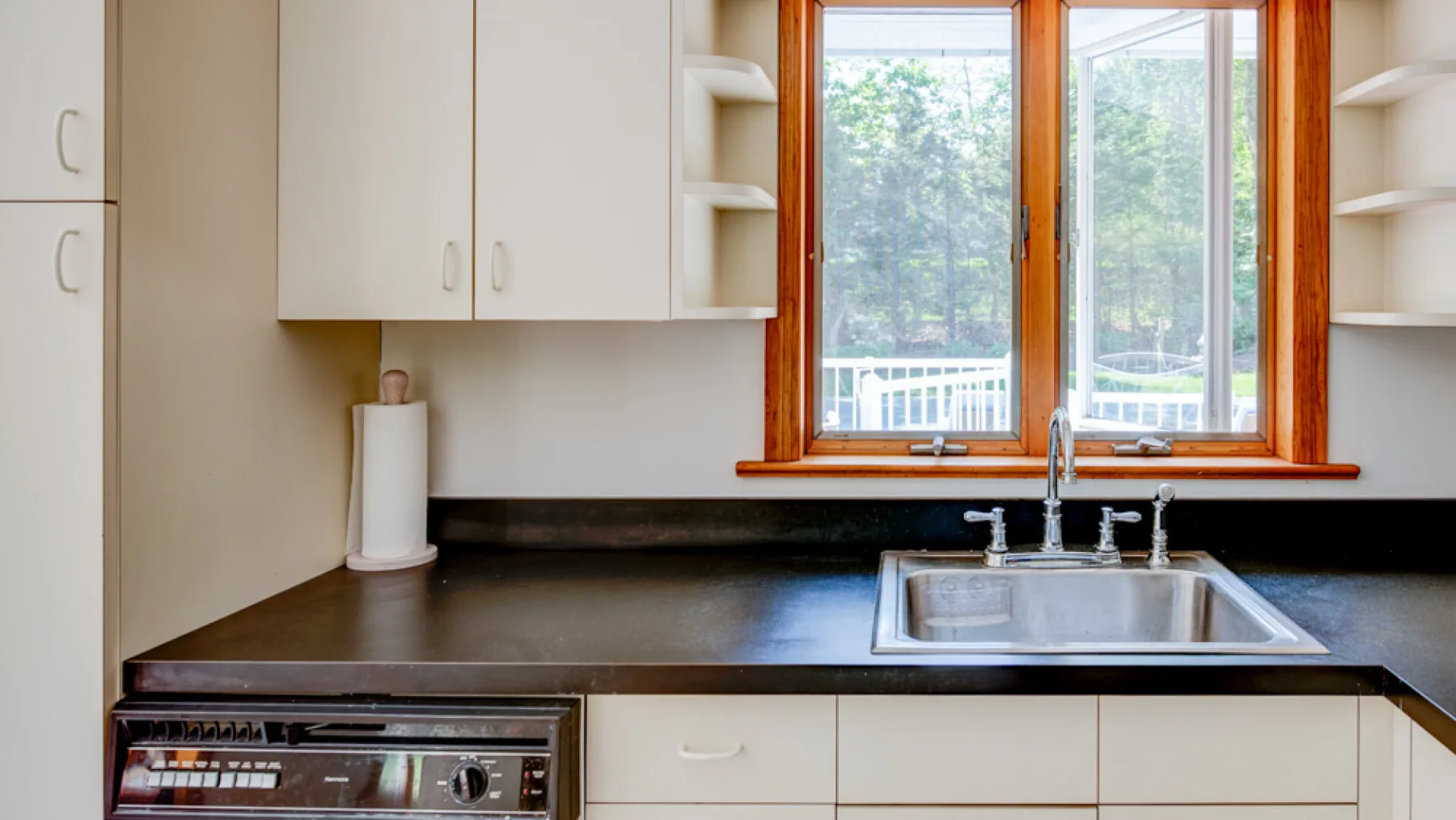 Una encimera de cocina con fregadero está bajo una ventana amplia.