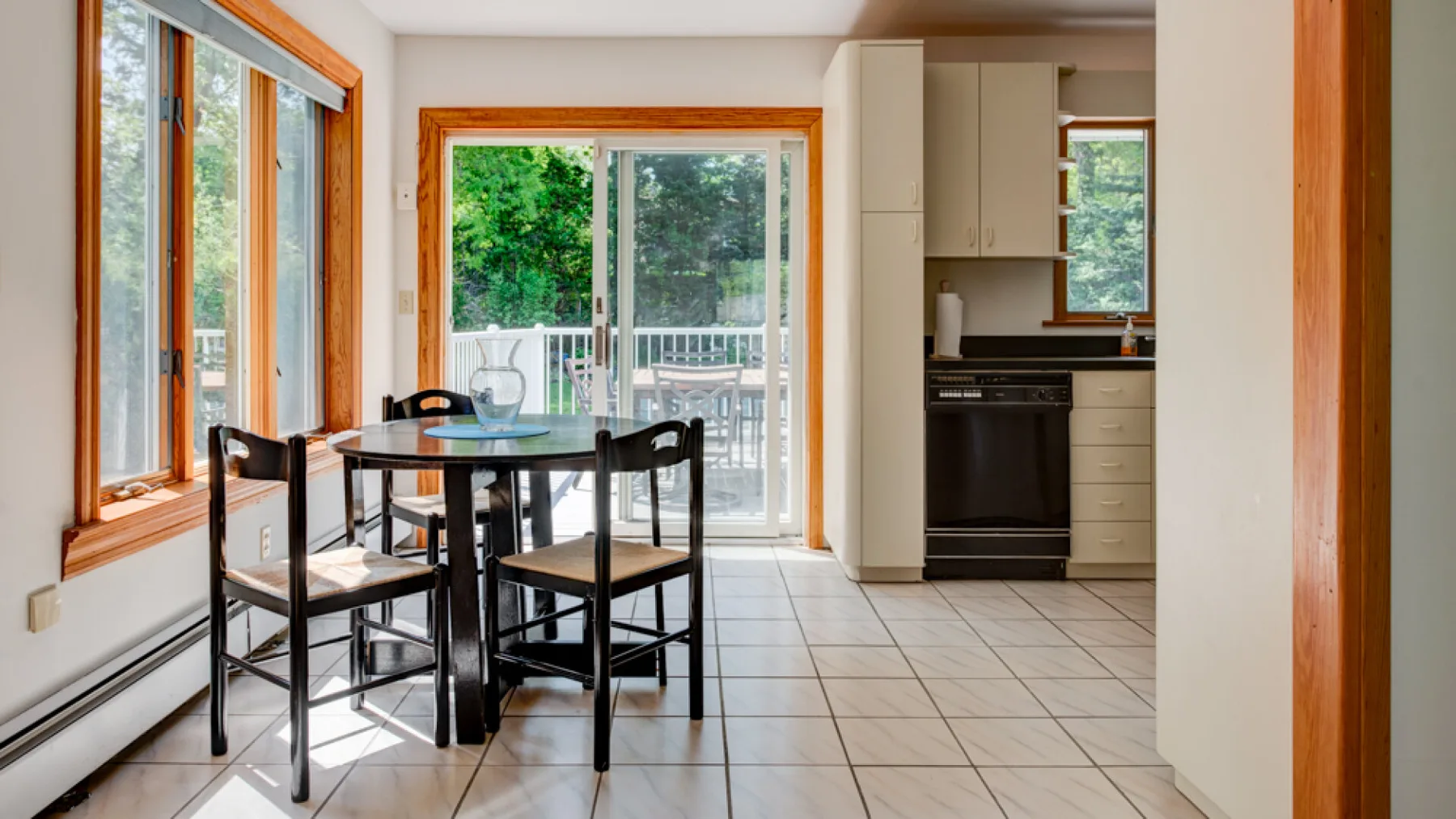 Comedor con una mesa junto a grandes ventanas y una puerta corrediza de vidrio.