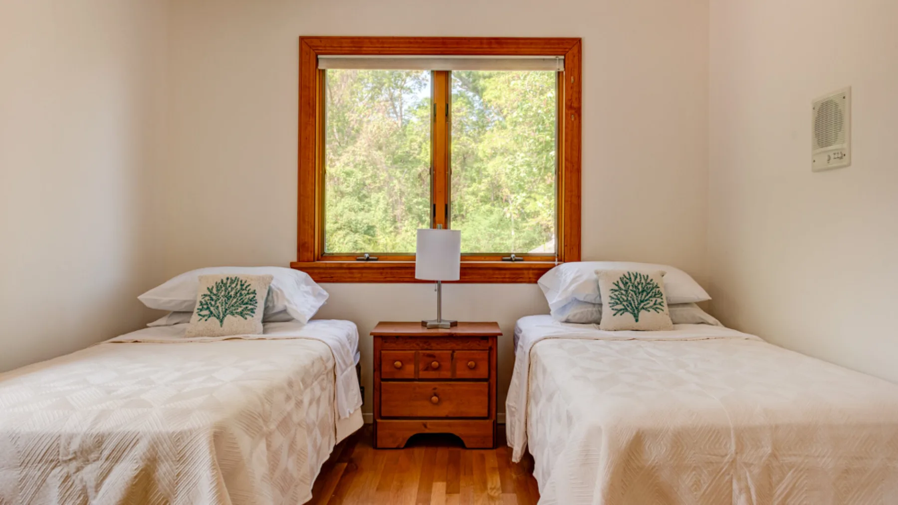 Un dormitorio con dos camas individuales y una mesita de madera bajo una ventana.