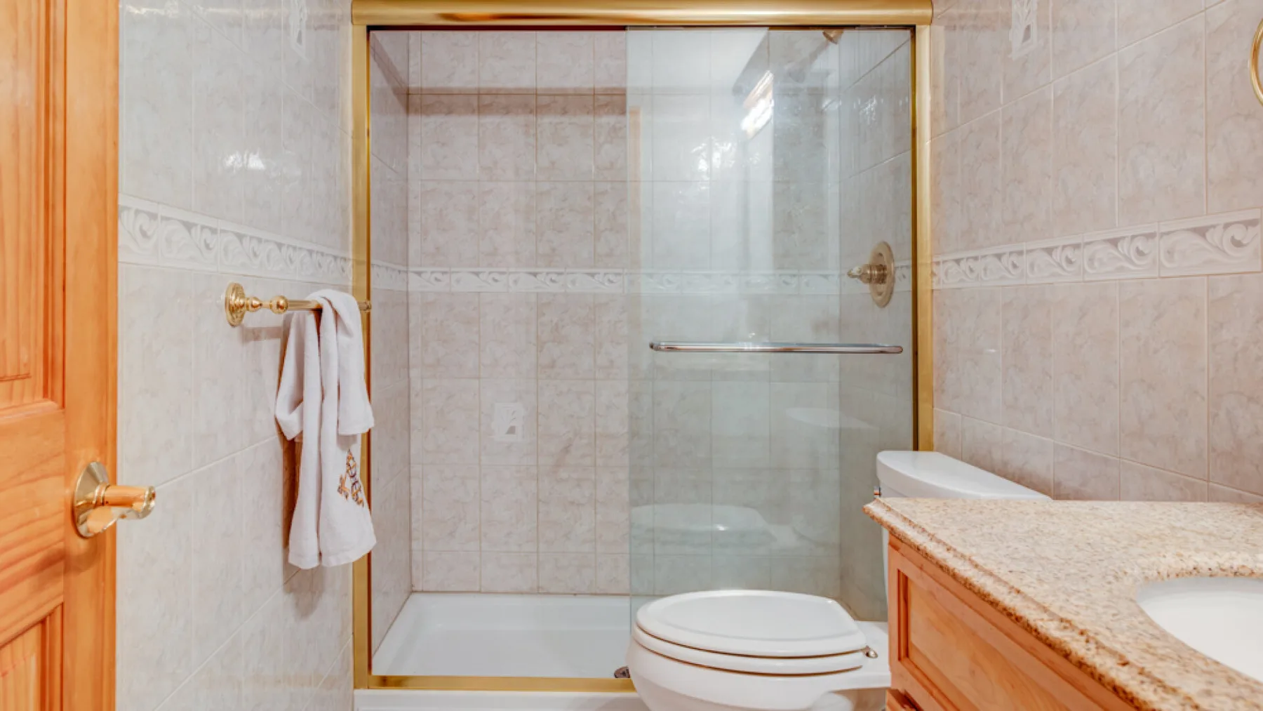 Un baño revestido de azulejos con ducha de vidrio y tocador.