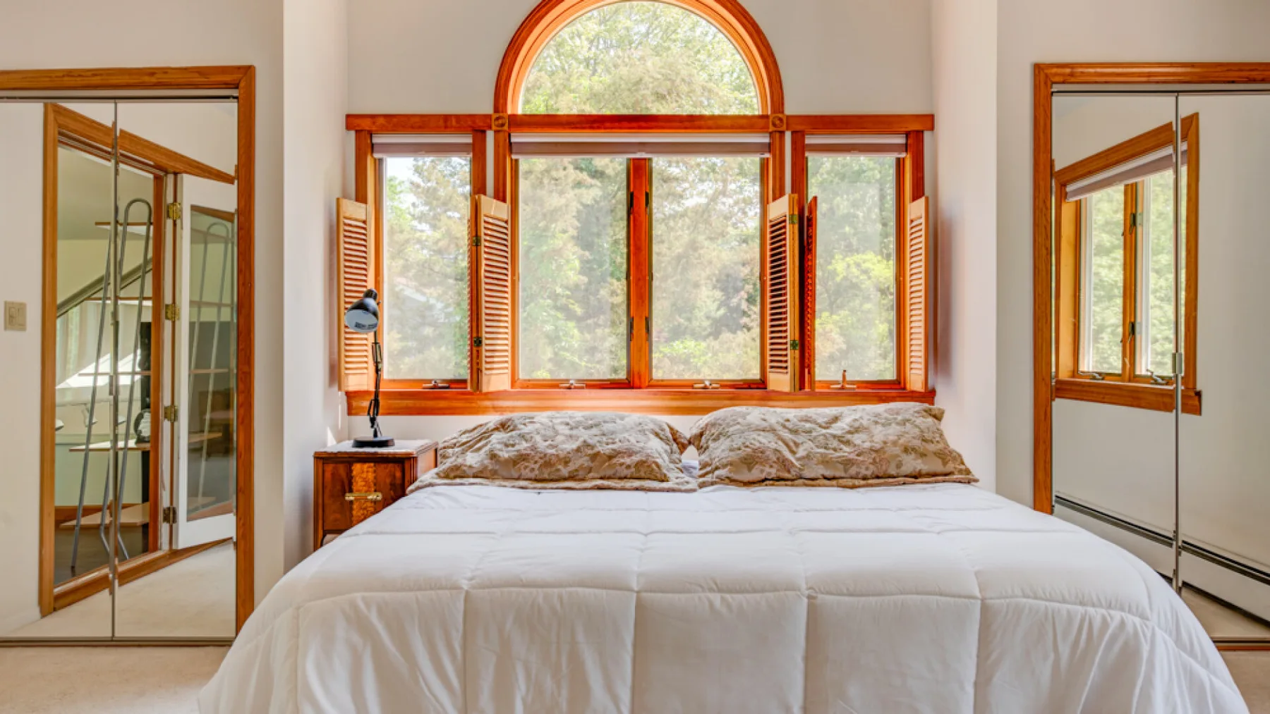 Un dormitorio con una cama grande bajo una ventana arqueada.