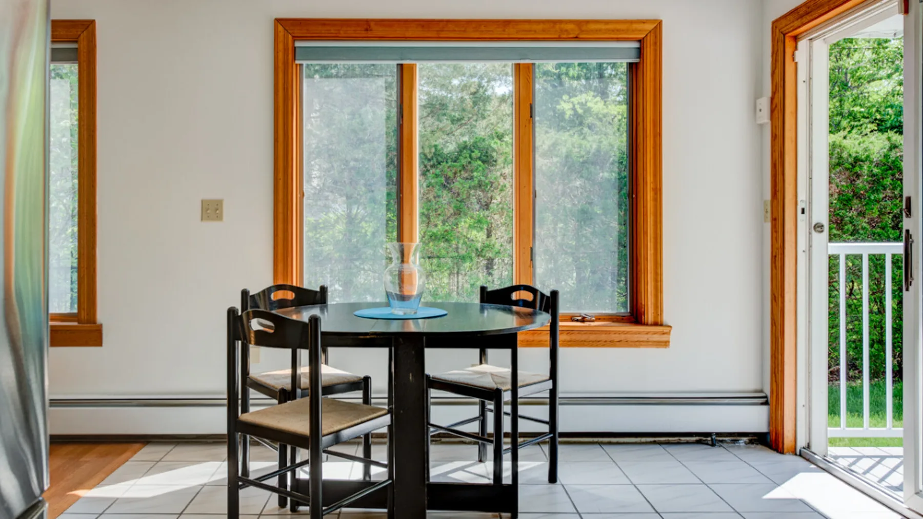 Un comedor con una mesa redonda y ventanas con vistas a la vegetación.