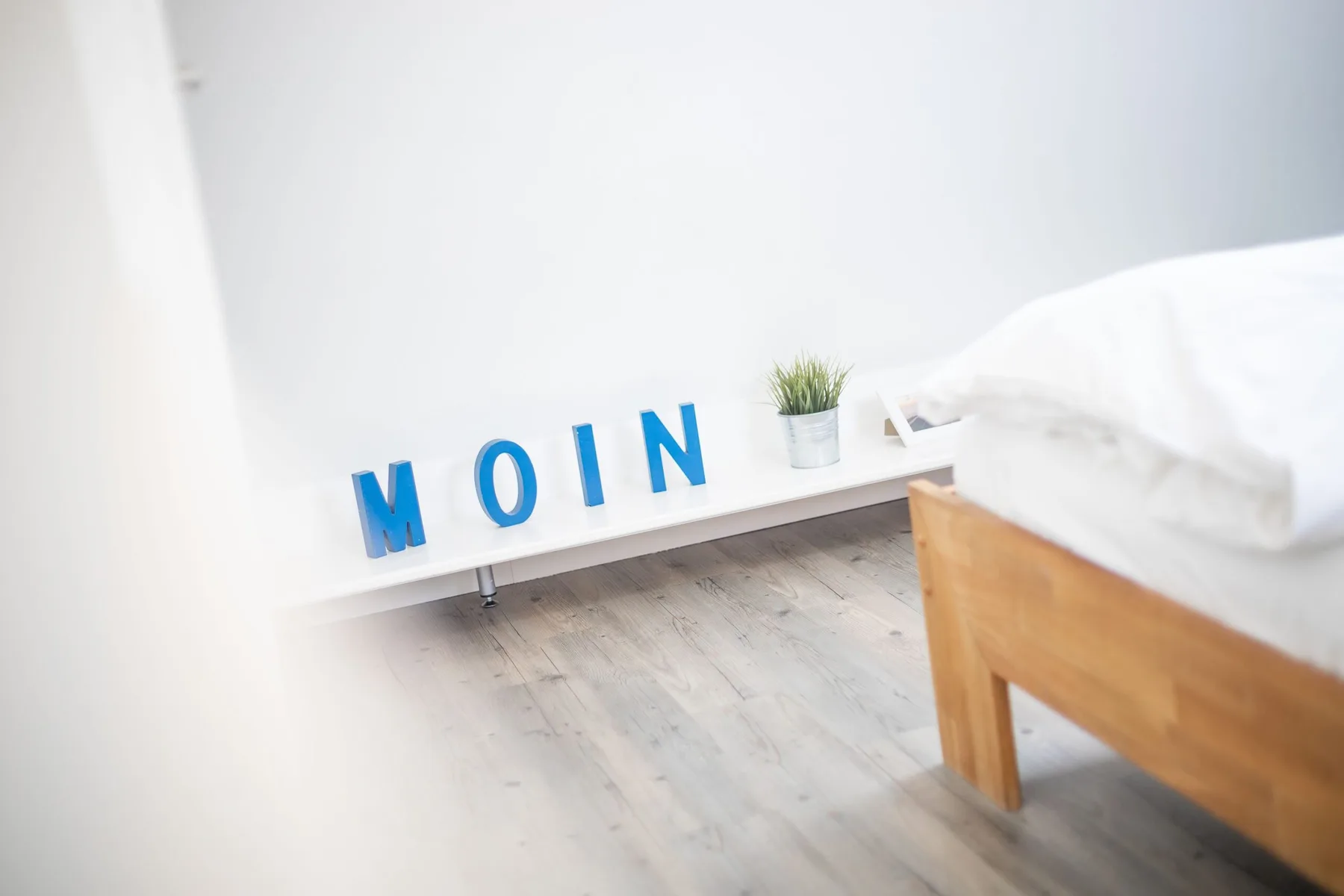 A bright bedroom with a wooden bed and blue letters on a shelf.