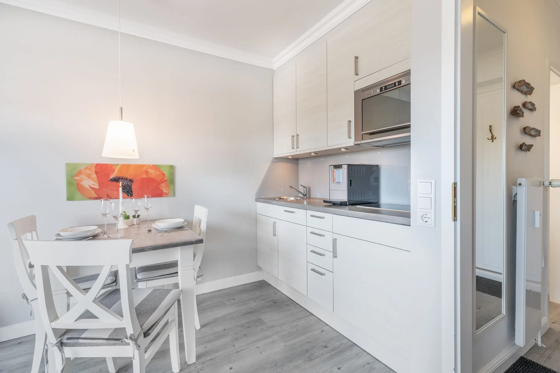 A bright dining area beside a compact kitchen with white cabinets.