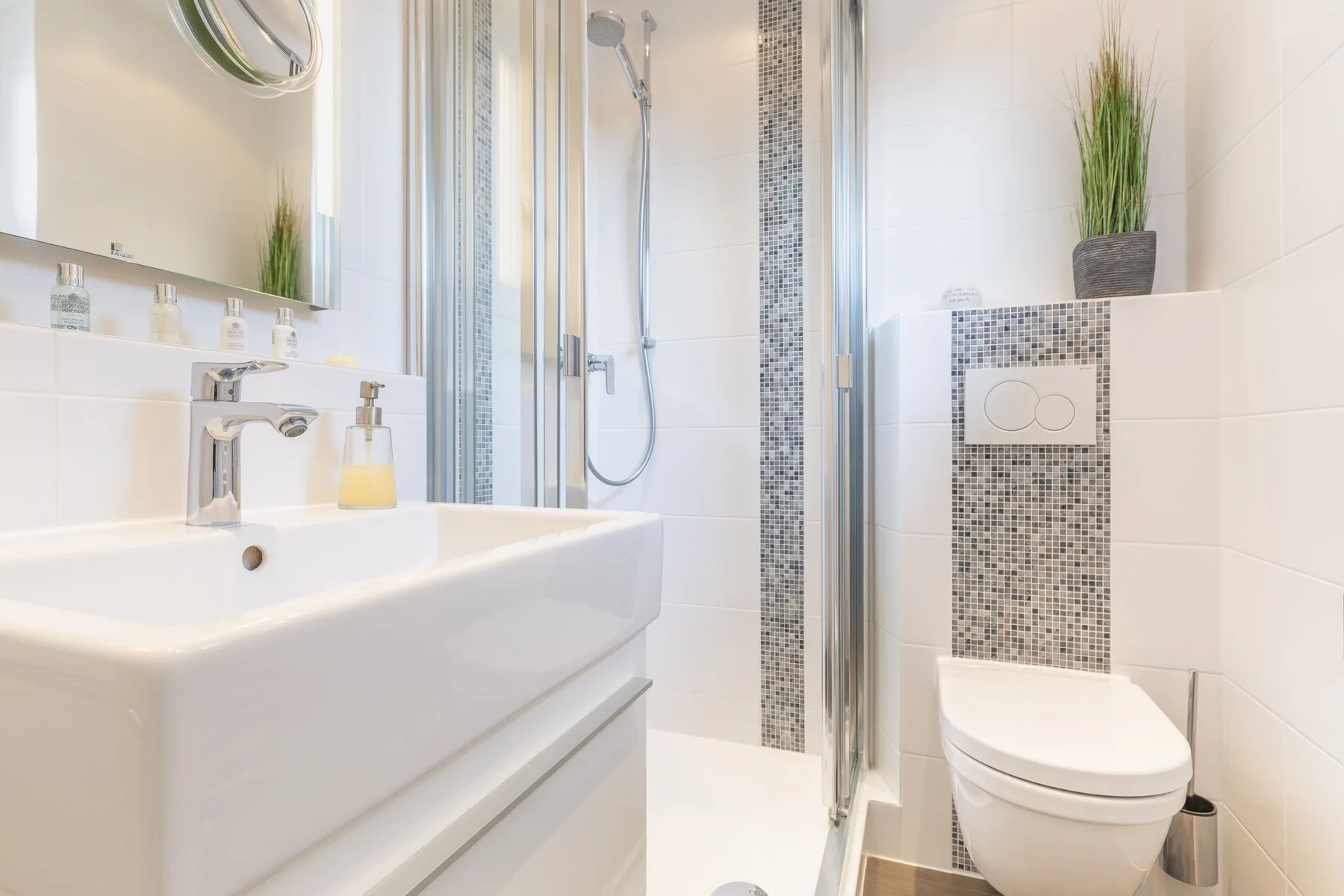A bright bathroom with a sink, toilet, and glass-enclosed shower.