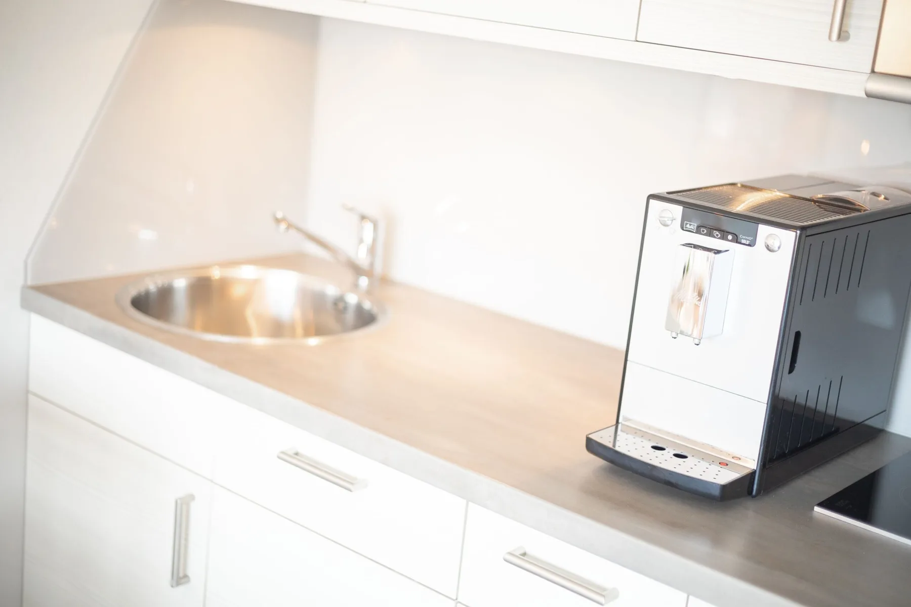 A kitchen counter with a sink and a coffee machine.