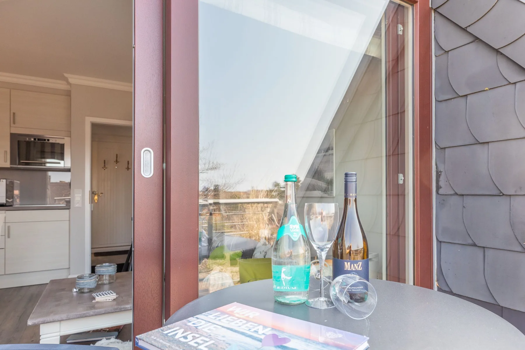 A sliding glass door opens onto a view of a kitchen and dining area.