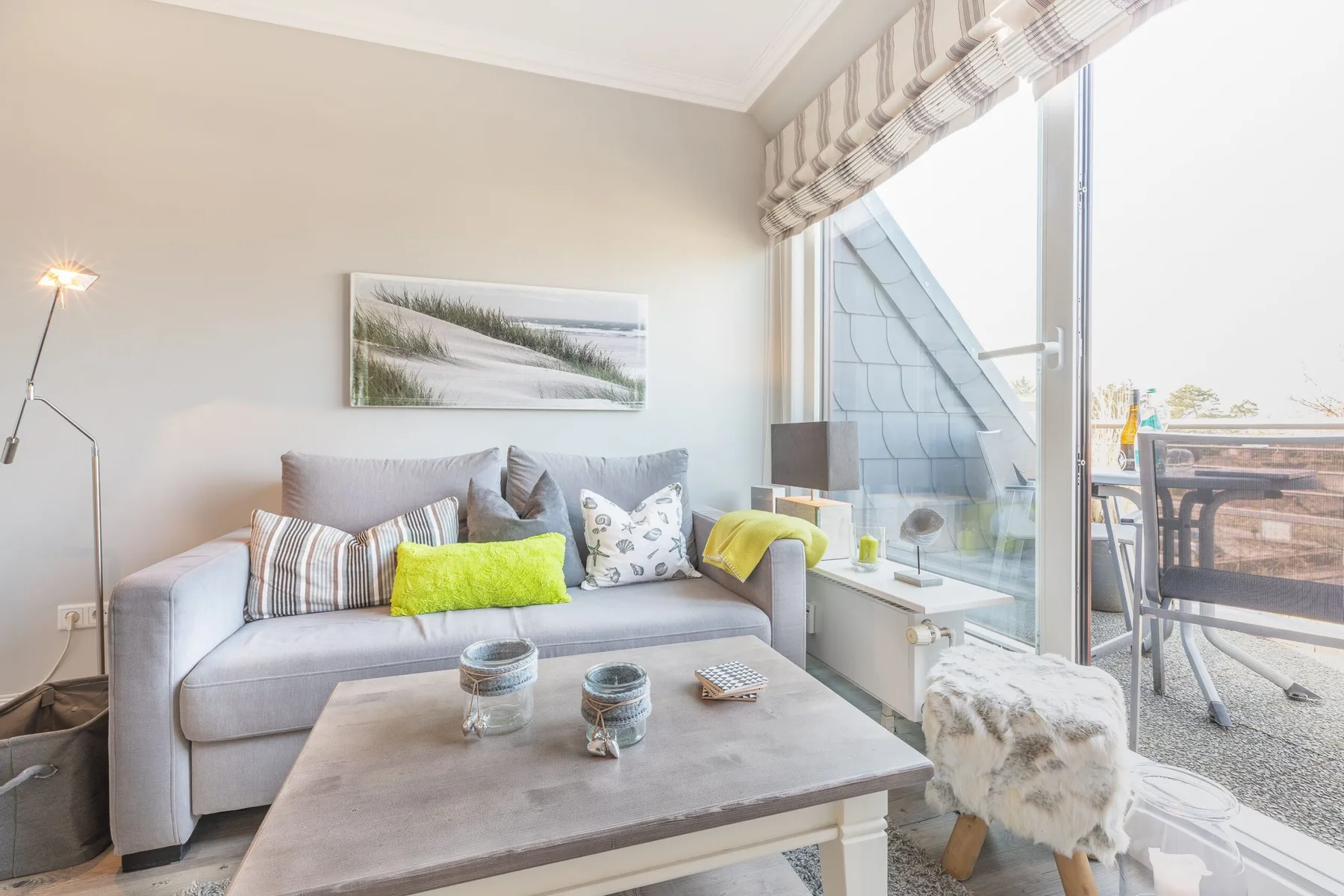 A bright living room with a gray sofa beside large glass doors.