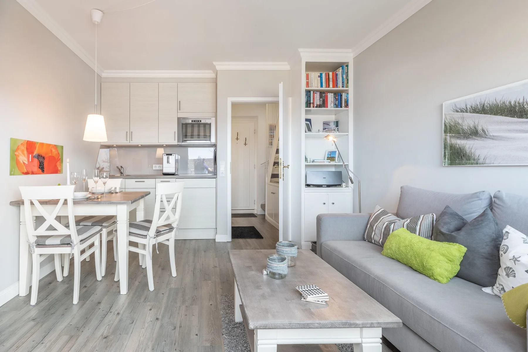 A bright open-plan living and dining area with a gray sofa and dining table.