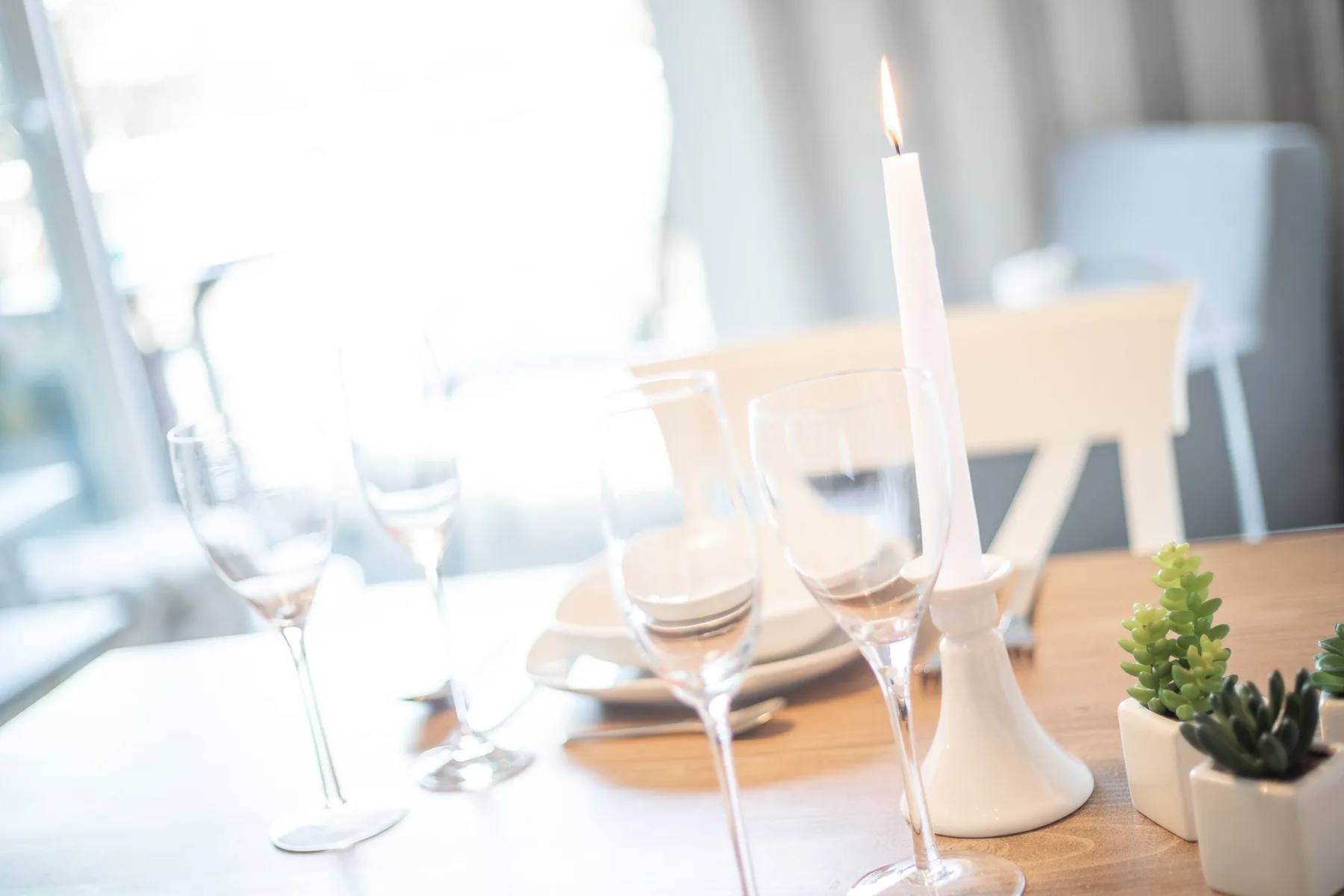 A dining table set with wine glasses and a lit candle.