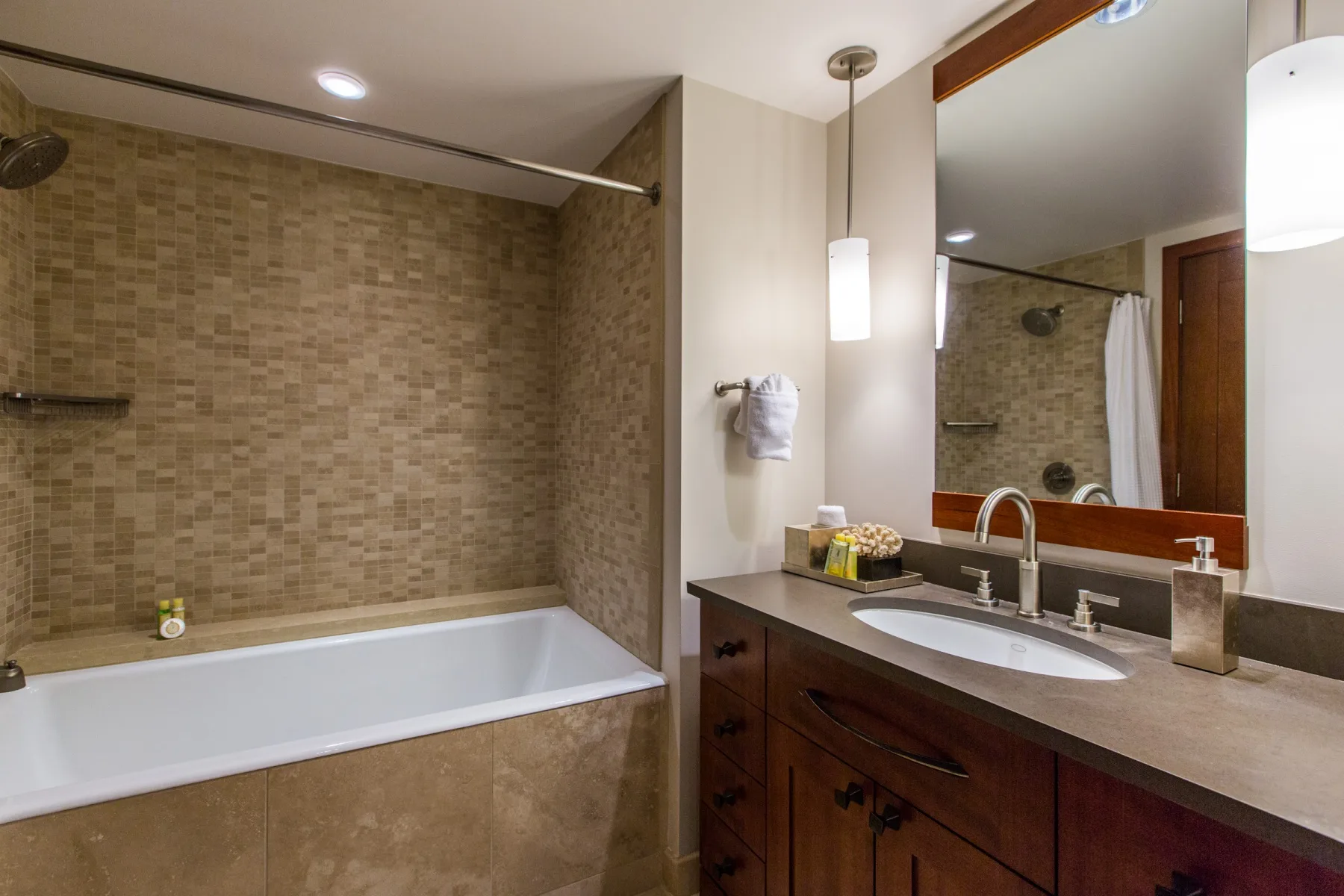 Un baño con bañera y un tocador bajo un espejo grande.