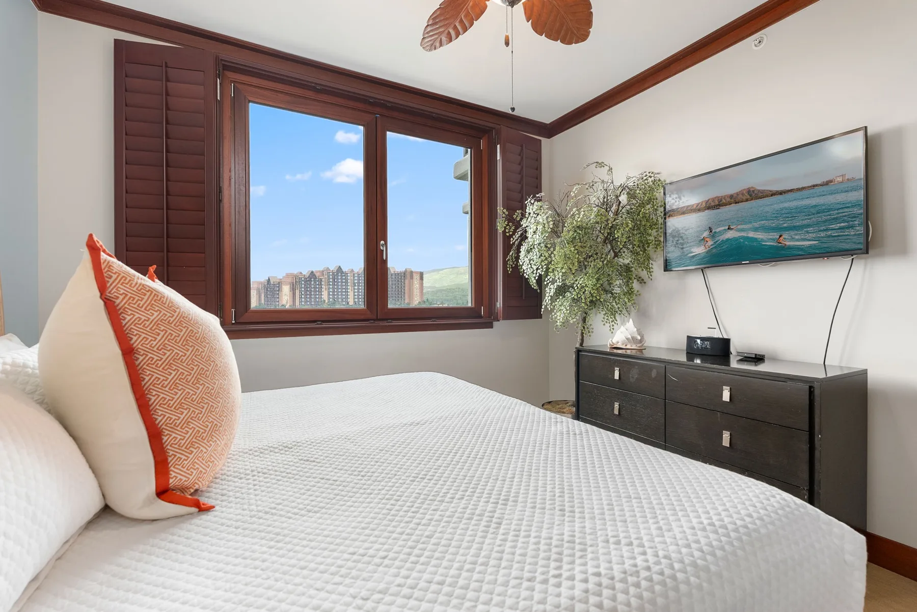 Un dormitorio con una cama bien tendida, una ventana grande y una cómoda.