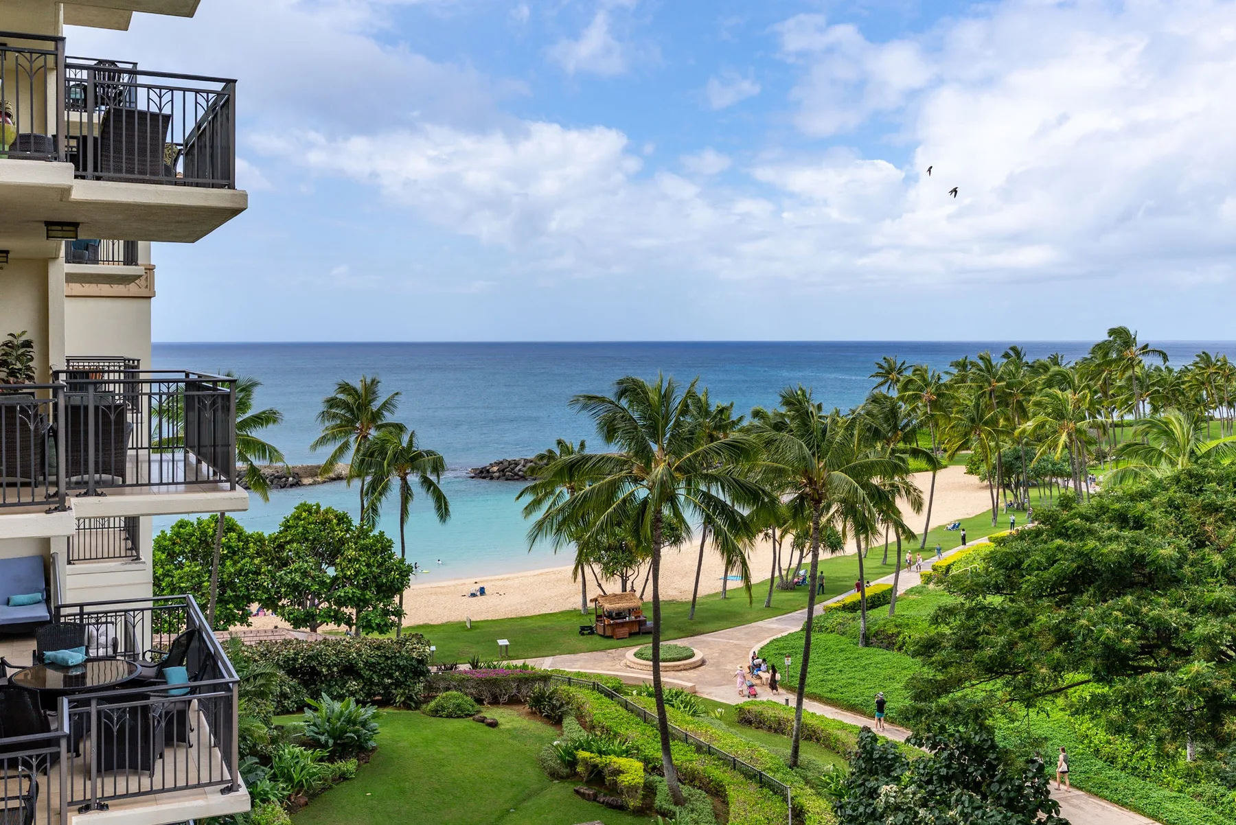 Una costa tropical con palmeras, una playa de arena y vistas al mar.