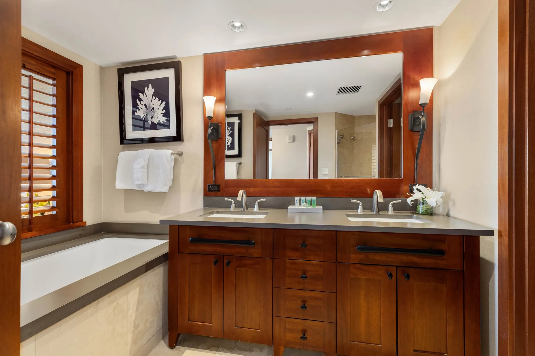 Un lavabo de baño con un espejo amplio y una bañera junto a la ventana.