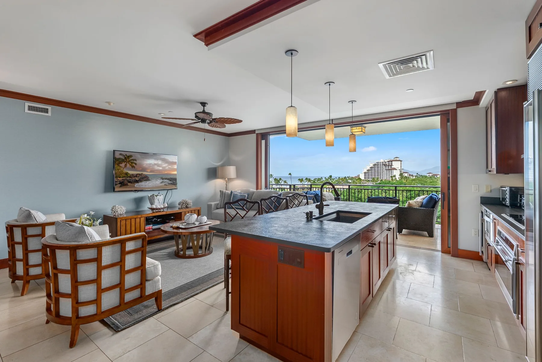 Una sala de estar y cocina abiertas, con una isla frente a un balcón.