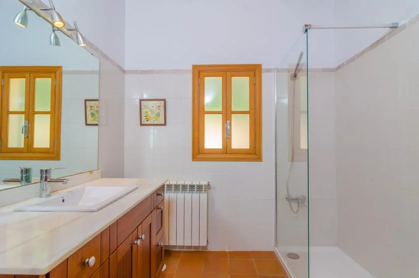 A tiled bathroom with a vanity, window, and glass shower.