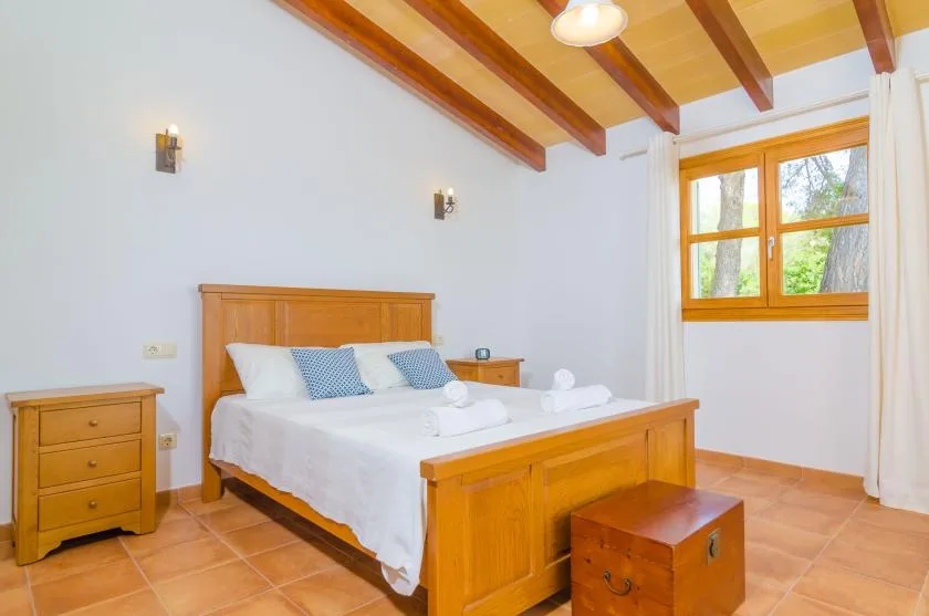 A bedroom with a wooden bed, white bedding, and a window.