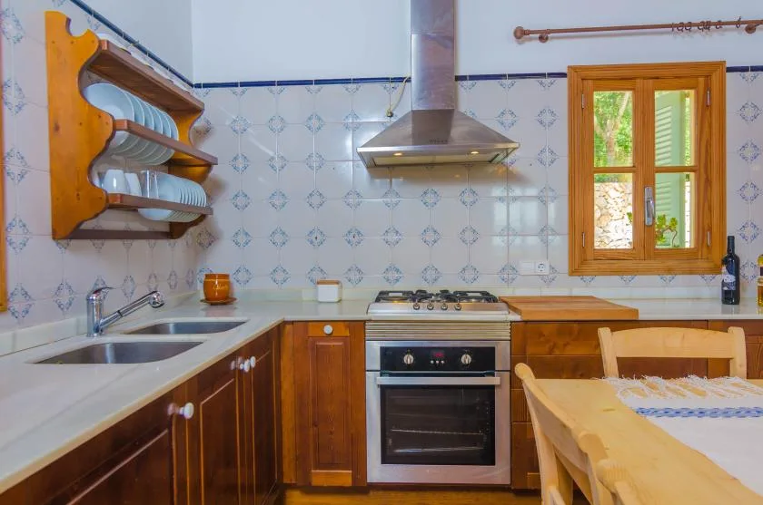 A kitchen with a cooktop, sink, and wooden dining table.