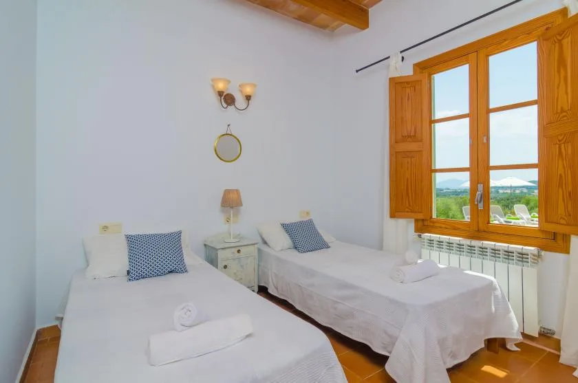 A bedroom with two single beds beside a wooden-framed window.