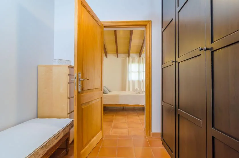 A bedroom is visible through an open wooden doorway beside a tall wardrobe.