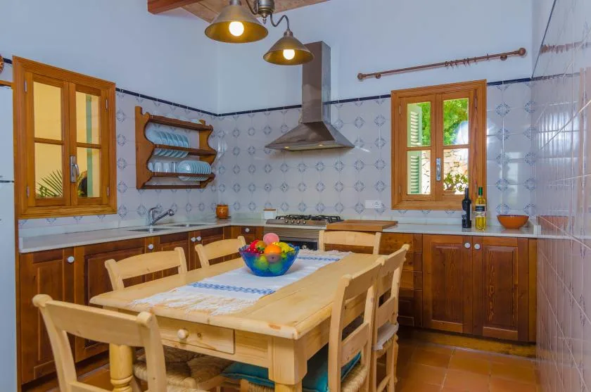 A tiled kitchen with wooden cabinets and a dining table in the foreground.