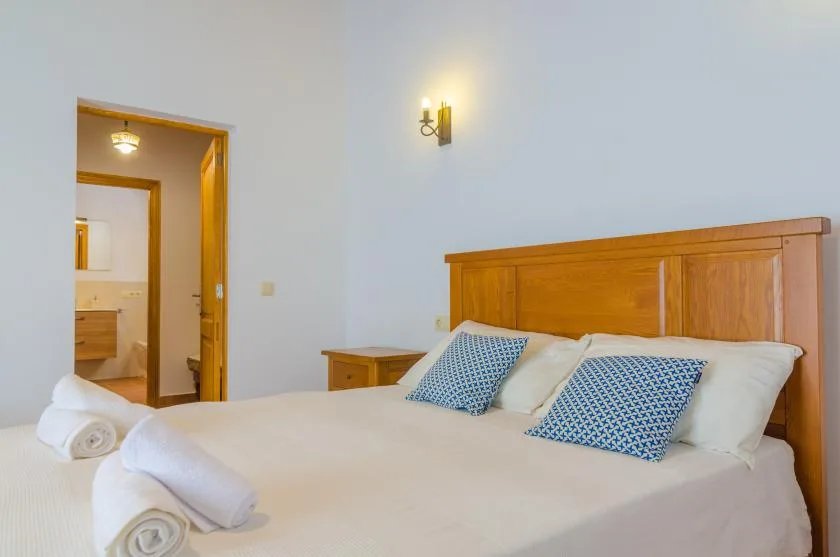 A bedroom with a bed, white bedding, and blue patterned pillows.