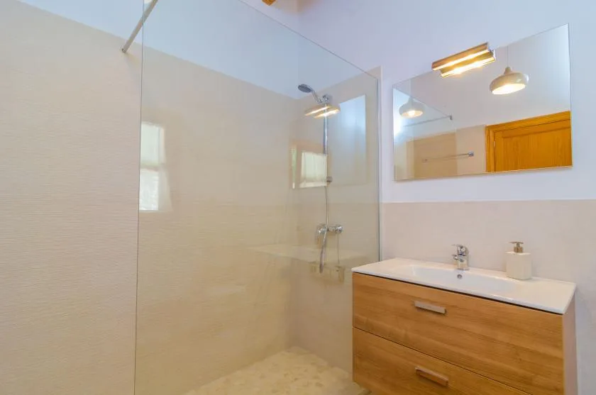 A bathroom with a glass shower, vanity, and wall mirror.