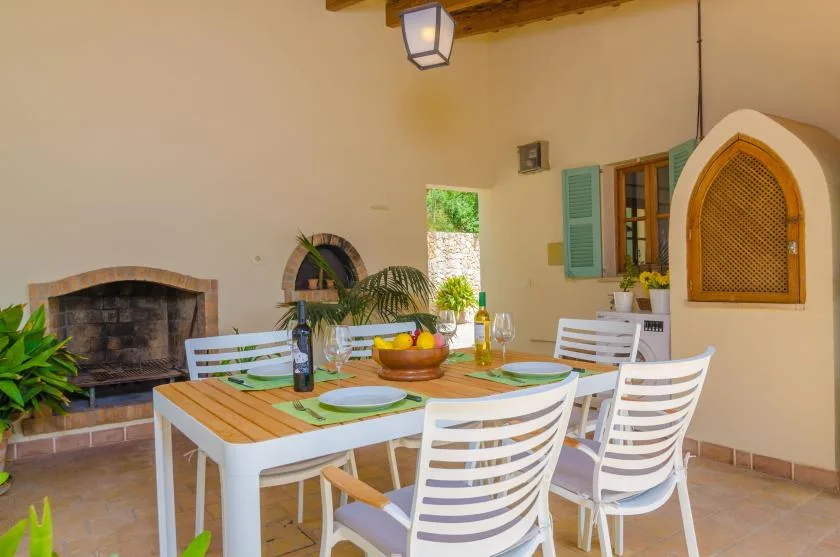 A covered patio dining area with a table set beside a built-in fireplace.