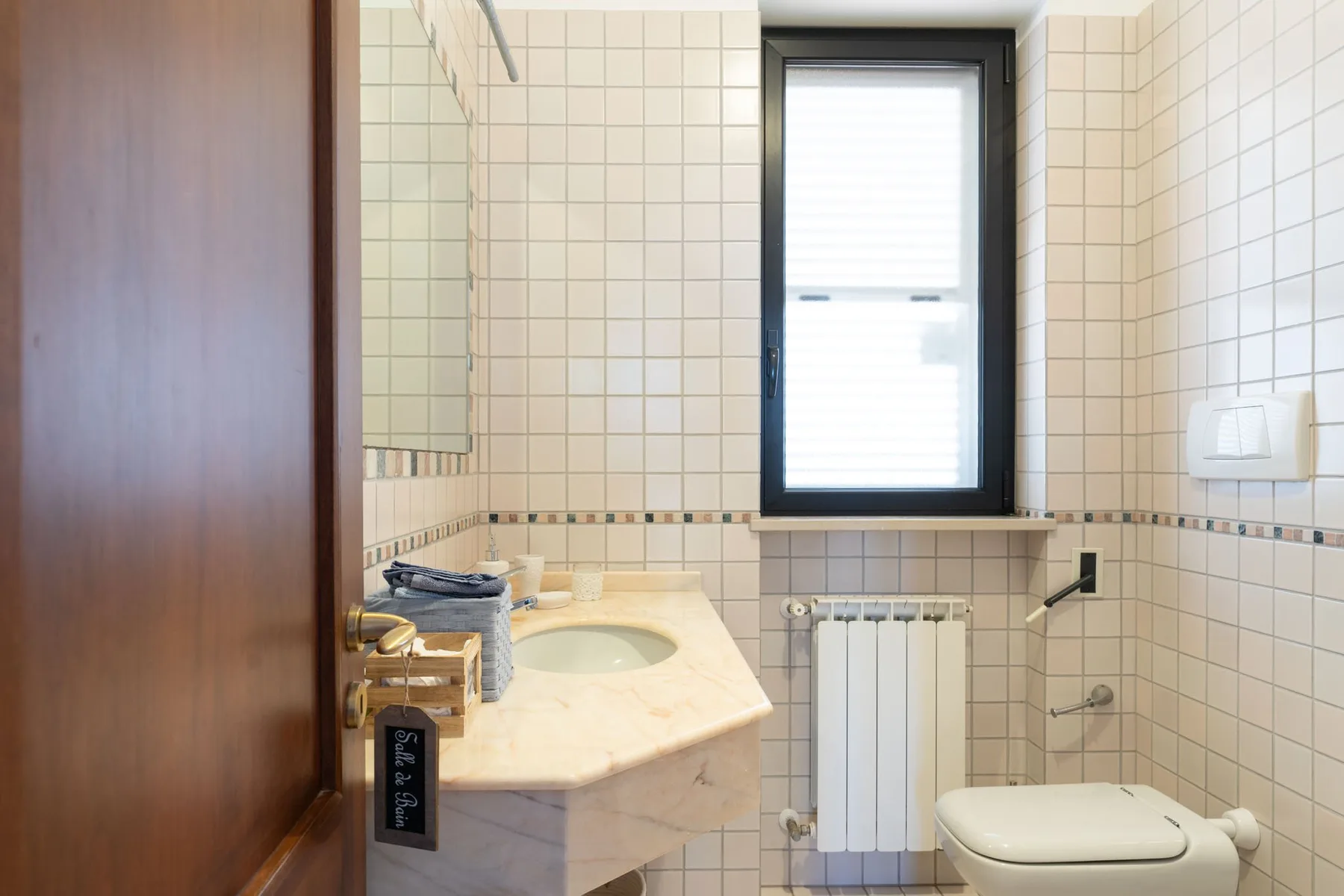 Un baño alicatado con lavabo, inodoro y ventana.
