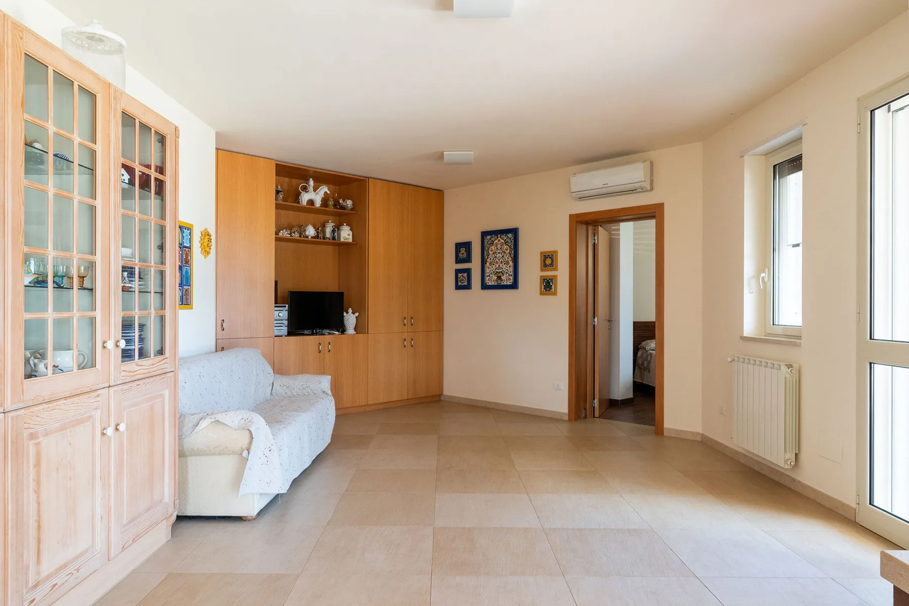 Una sala luminosa con un armario con puertas de vidrio y un televisor.