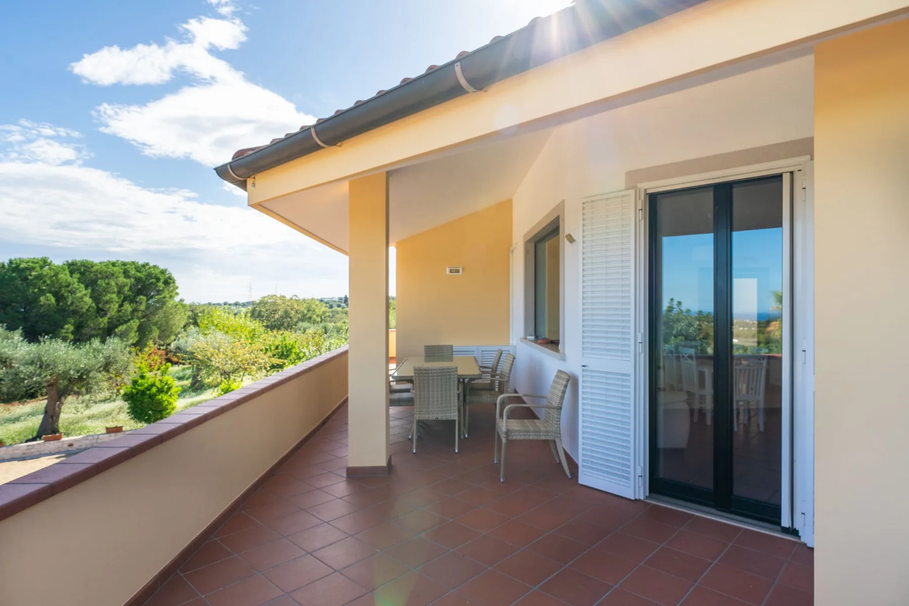 Una terraza exterior cubierta con asientos y puertas corredizas de vidrio.