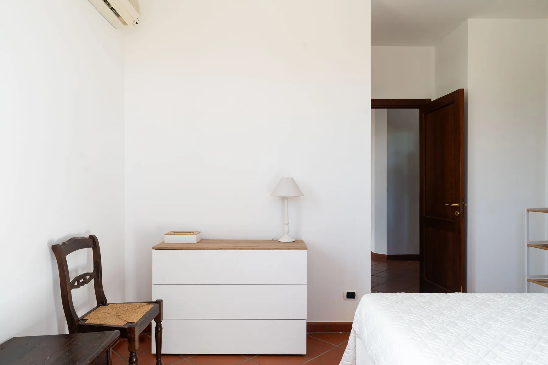 Un dormitorio con una cama, una cómoda y una puerta abierta.