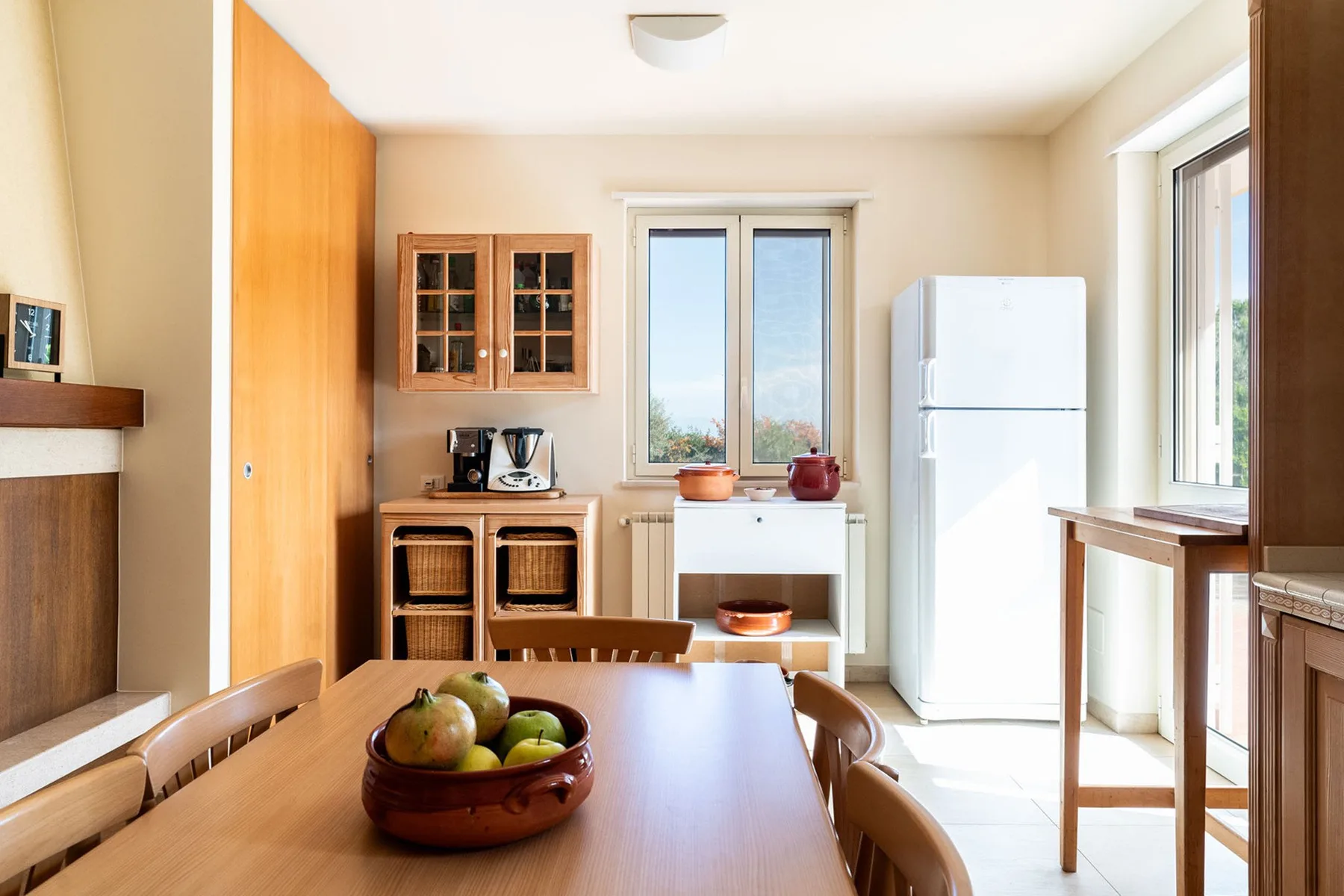 Una cocina y comedor luminosos con una mesa de madera y ventanas grandes.