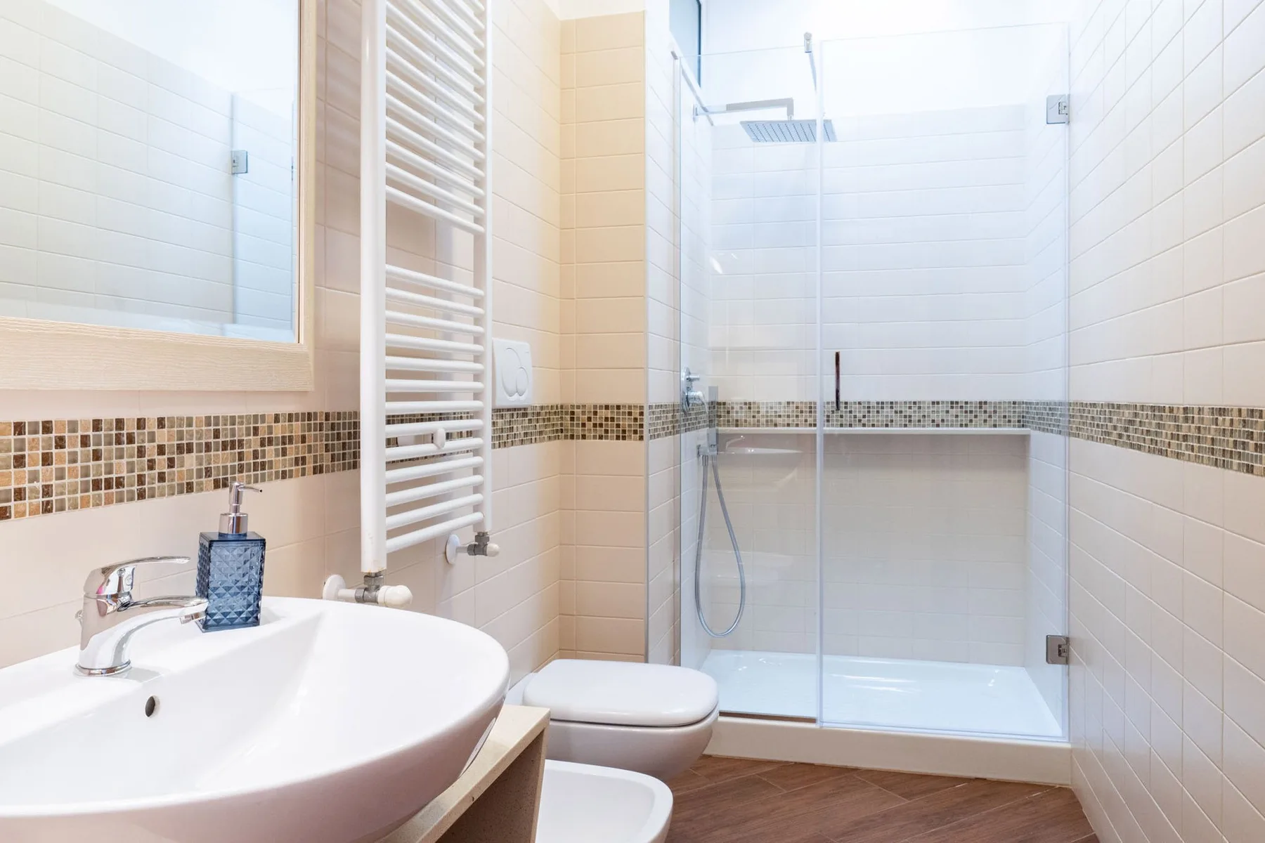 Un baño alicatado con lavabo y ducha de vidrio.