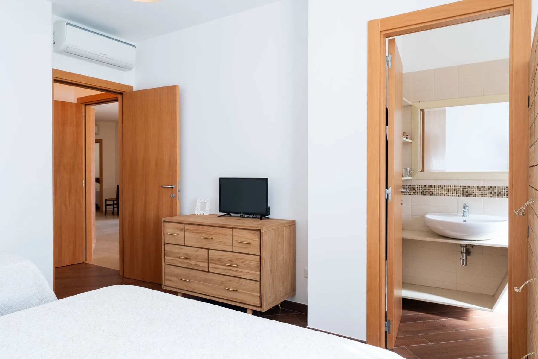 Un dormitorio con una cómoda de madera y una puerta que da a un baño.